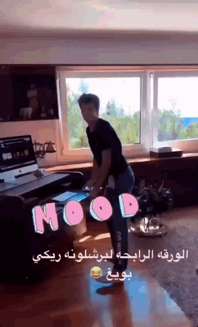 a man in a black shirt is standing in front of a desk with the word mood written on it