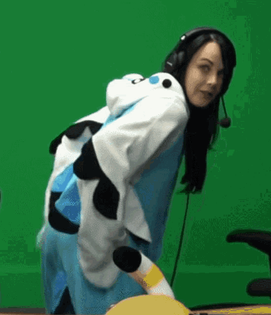 a woman wearing headphones and a panda costume is holding a stuffed animal .