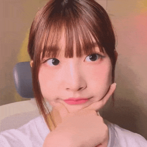 a girl with bangs is making a face with her hand on her chin