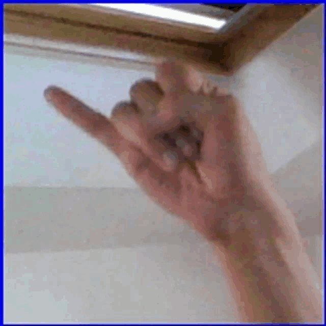 a person 's hand is pointing up at a window