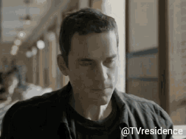 a man in a black shirt is sitting at a table with his eyes closed