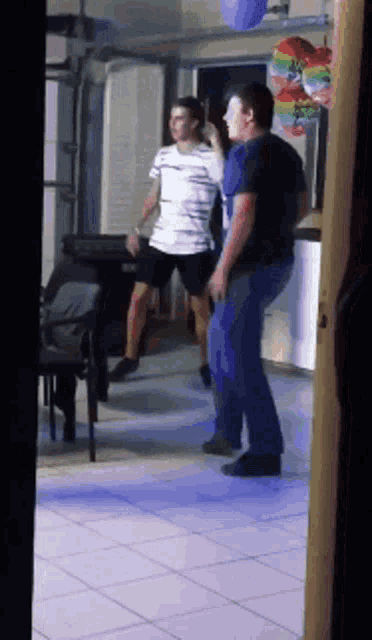 a group of men are dancing in a room with balloons hanging from the ceiling