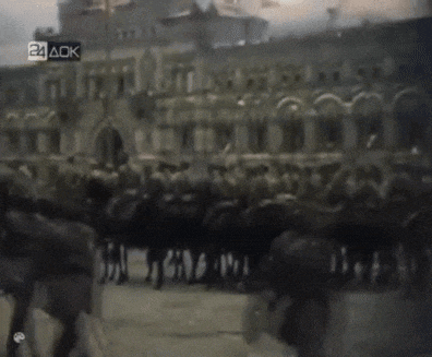 a group of people are marching in front of a building with the letters 24 ack on the bottom right