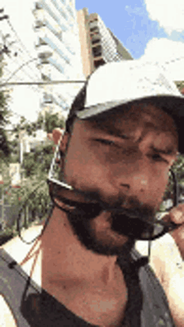 a man with a beard wearing sunglasses and a baseball cap .