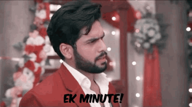 a man in a red suit says " ek minute " on the bottom