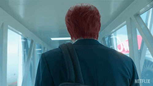 a man with red hair is walking down a hallway with netflix written on the bottom
