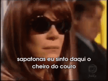 a woman wearing sunglasses with the words " sapatonas eu sinto daqui o cheiro do couro " below her