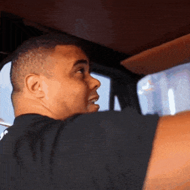 a man in a black shirt is sitting in a car