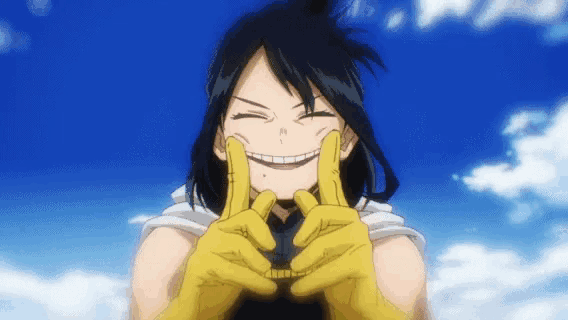 a girl with black hair and yellow gloves is smiling and making a heart with her hands .