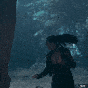 a woman is running in a dark room with the word macha on the bottom left