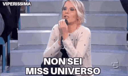 a woman is singing into a microphone and saying non sei miss universo .