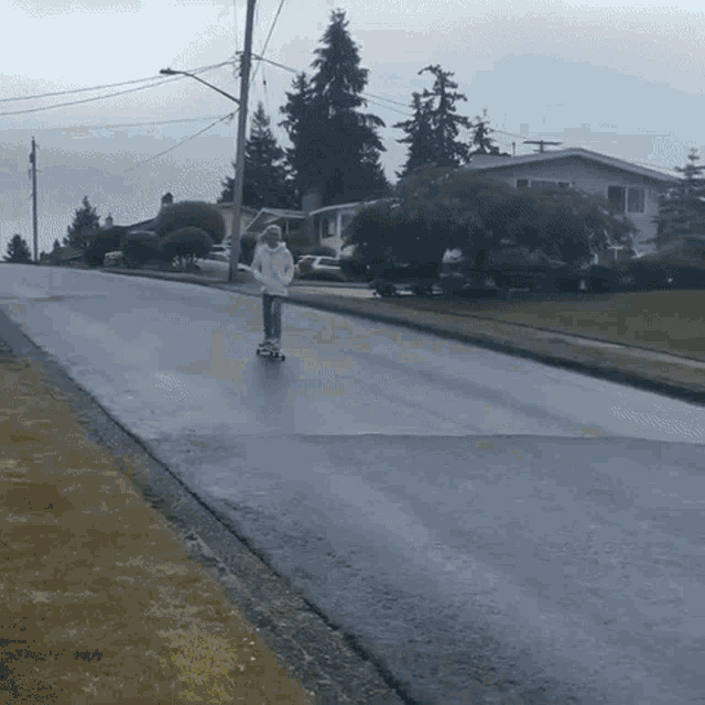 a person is riding a skateboard down a street in the rain