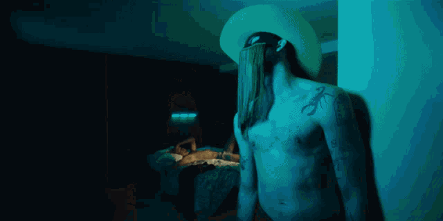 a man without a shirt is standing in a dark room wearing black underwear .