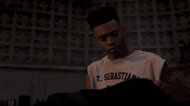 a man wearing a t. sebastian t-shirt looks down at something