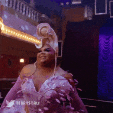 a drag queen is wearing a pink and white dress with flowers on it