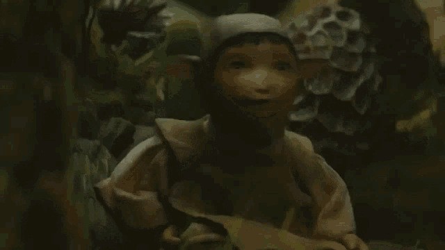 a close up of a doll sitting in the woods .