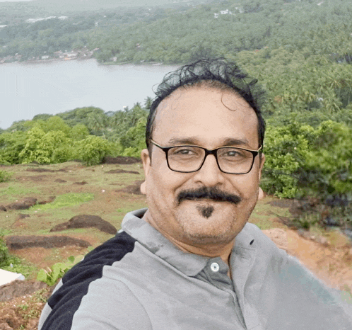 a man with glasses and a mustache is taking a selfie