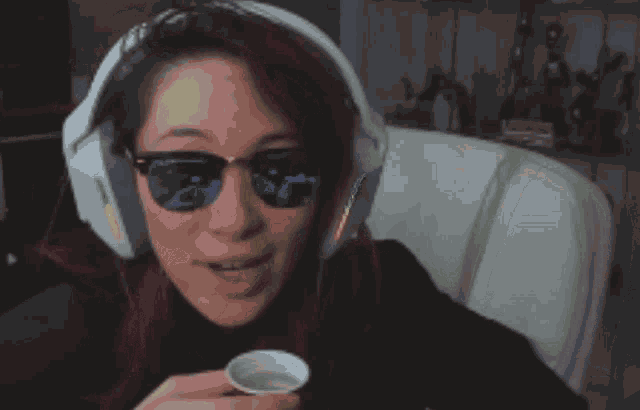 a woman wearing headphones and sunglasses is eating