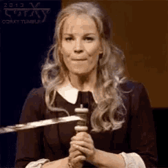 a woman is holding a sword in her hands and smiling .