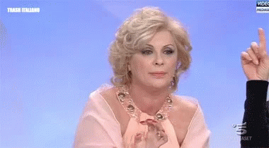 a woman in a pink dress is pointing her finger up