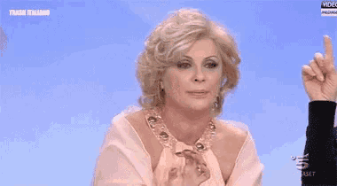 a woman in a pink dress is pointing her finger up