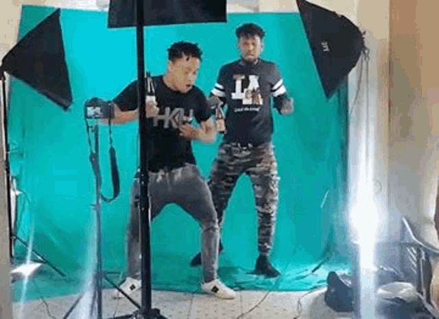 two men are posing for a picture in front of a green screen in a studio .