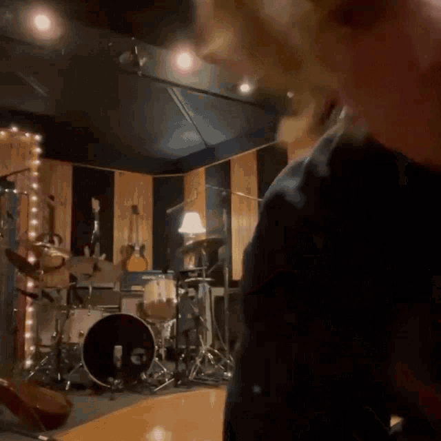 a person standing in front of a drum set in a room