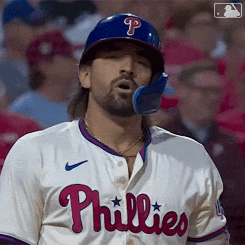 a phillies baseball player wears a blue helmet and a white jersey