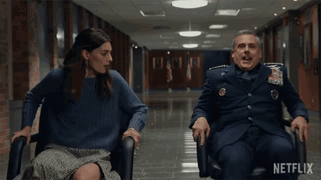 a man in a military uniform sits in a wheelchair next to a woman who is sitting in a chair