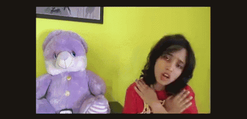 a girl is sitting next to a purple teddy bear
