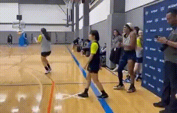 a group of people are standing on a basketball court in a gym .