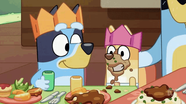 two cartoon dogs wearing crowns sit at a table eating food
