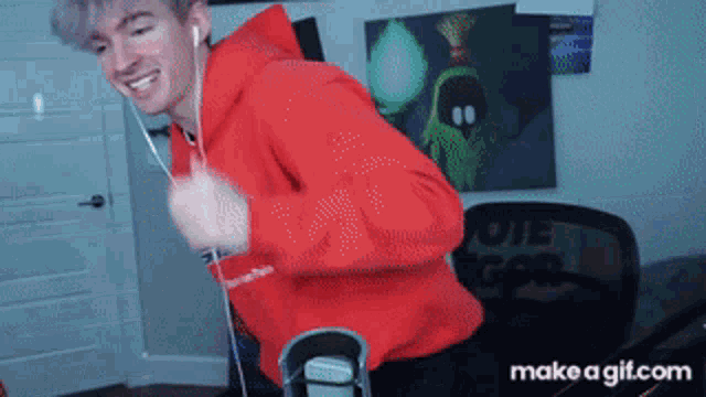 a man in a red hoodie is dancing in front of a make a gif.com screen