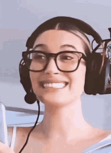 a woman wearing glasses and headphones is smiling while holding a cell phone .