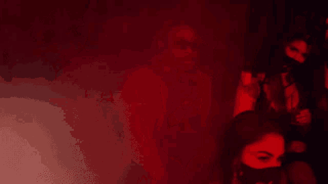 a man and a woman are standing in a dark room with red lights