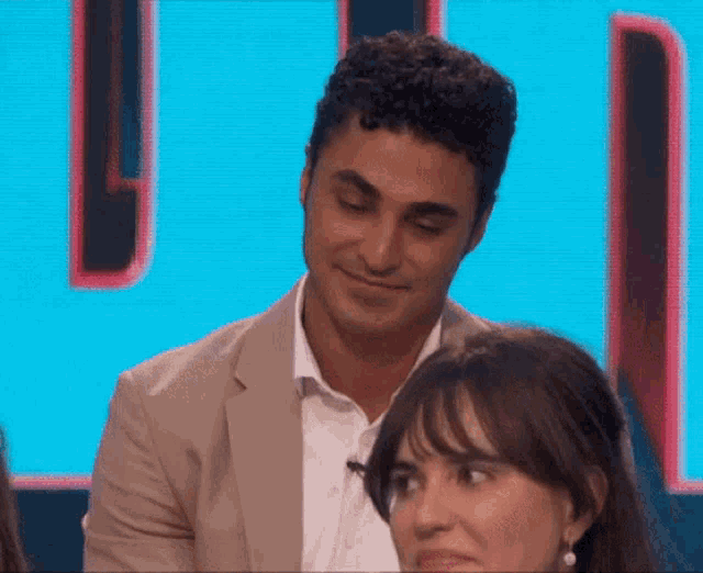 a man in a suit looks over a woman 's shoulder in front of a sign that says u.