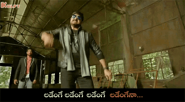 a man in a suit and sunglasses is dancing in a room with a caption in telugu