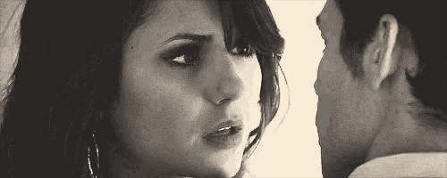 a black and white photo of a man and a woman looking into each other 's eyes .