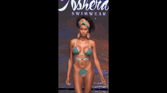 a woman in a bikini is walking down a runway .