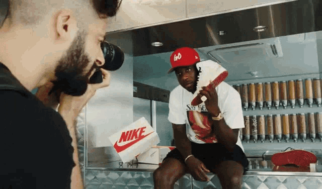 a man is taking a picture of a man holding a nike box