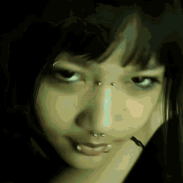 a close up of a woman 's face with piercings on her nose and lips .