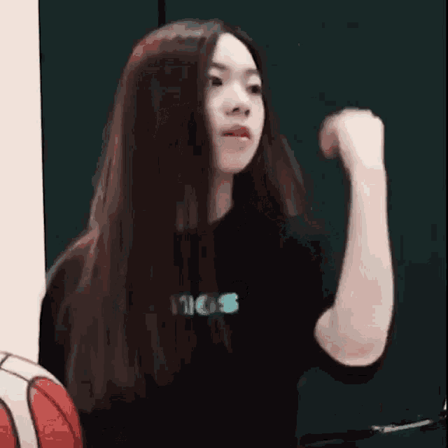 a woman with long hair is standing in front of a basketball and making a funny face .