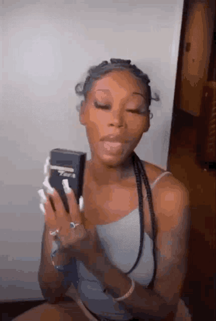 a woman is holding a cell phone in her hand and looking at it .