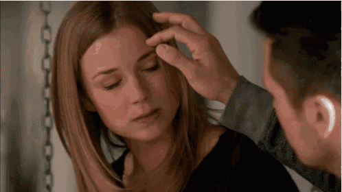 a man is touching a woman 's head with his finger .