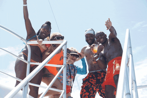 a man wearing orange x fenty shorts poses with a group of people