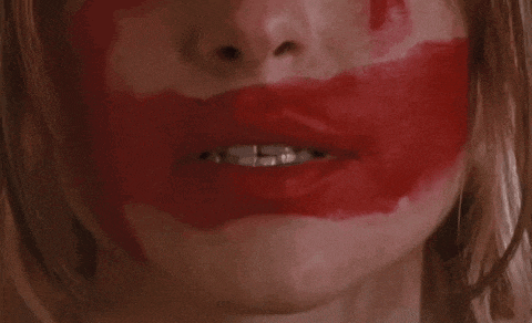 a close up of a woman 's face with red lipstick on her lips .