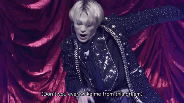 a man in a black jacket says " don 't you ever wake me from this dream " in front of a red curtain