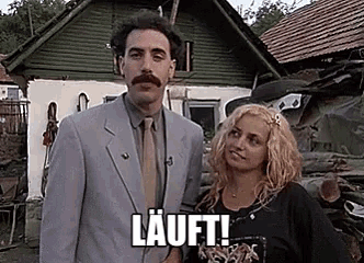 a man in a suit and tie is standing next to a woman in front of a house and says `` lauft '' .