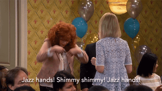 a group of women are standing in a room with balloons and one of them is saying jazz hands