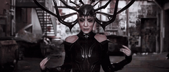 a woman in a black costume with horns on her head is standing in a building .